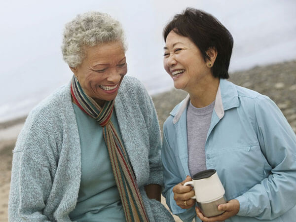 Two laughing women on the beach in winter